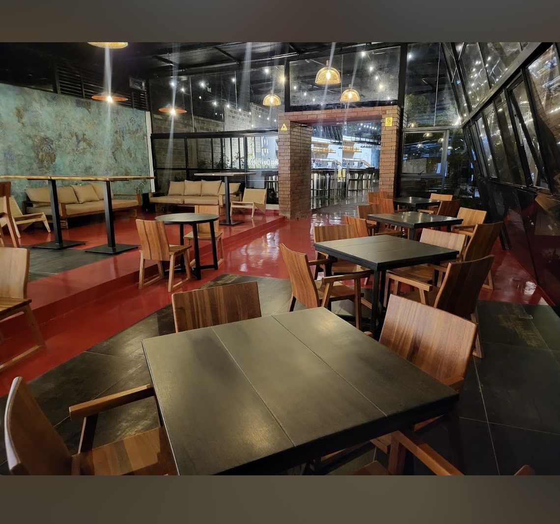 Wide view of the dining room with warm pendant lighting, lounge seating and glass walls