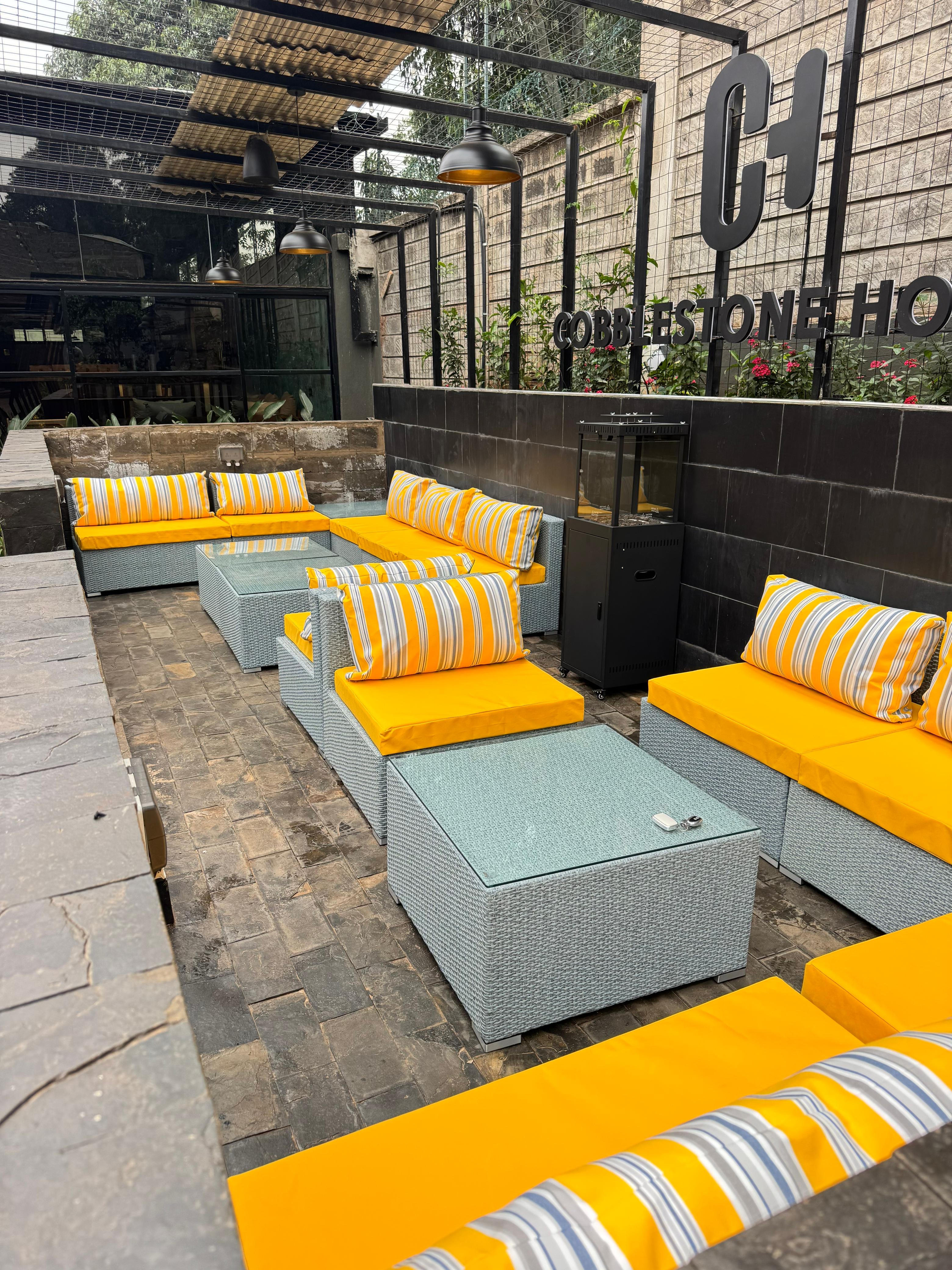 Outdoor terrace lounge with golden seating beneath the Cobblestone House signage